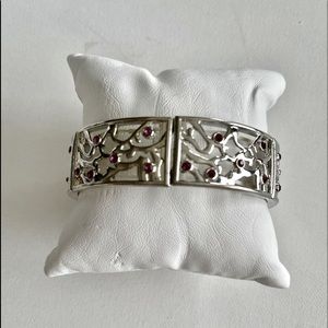 Very pretty sliver tone with dark pink jewels inlaid throughout. One size